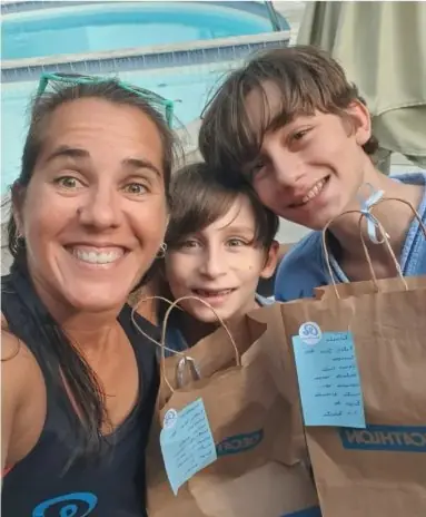 Roberta com dois alunos irmãos segurando presentes do Dia das Crianças